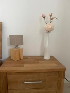 a white vase with a flower on a wooden table at Albblick in Albstadt