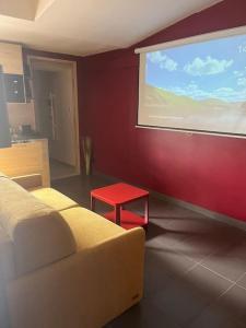 Habitación con una gran pantalla de proyección y una mesa roja. en Suite avec Sauna 36m², en Niort