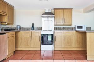 a kitchen with wooden cabinets and a white oven at The Barn (Chilsworthy), 6 Sleeper House, 19 Min Drive into Bude, Cornwall in Holsworthy