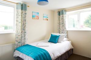 a bedroom with a bed with blue and white pillows at The Barn (Chilsworthy), 6 Sleeper House, 19 Min Drive into Bude, Cornwall in Holsworthy
