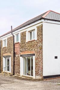 a brick building with a large white garage at The Barn (Chilsworthy), 6 Sleeper House, 19 Min Drive into Bude, Cornwall in Holsworthy