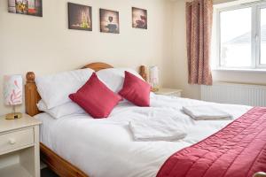 a bed with red and white pillows and a window at The Barn (Chilsworthy), 6 Sleeper House, 19 Min Drive into Bude, Cornwall in Holsworthy