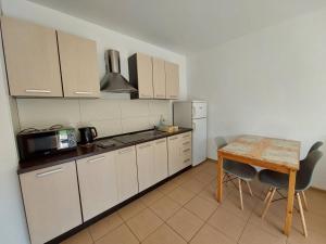 a kitchen with white cabinets and a table and a refrigerator at Domki Letniskowe Flauta in Grzybowo +2 photos