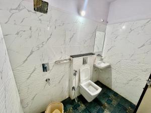 a white bathroom with a toilet and a sink at Hotel Kiwi Inn in Indore