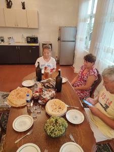 a group of people sitting around a table with food at House Dea Dea in Chakvi