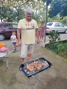 a man standing next to a grill with sausages at House Dea Dea in Chakvi