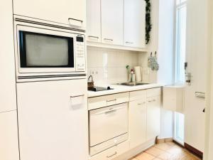 eine weiße Küche mit Mikrowelle und Spüle in der Unterkunft Wohlfühl Strand Wohnung 'Mein Ankerplatz' in Lübeck