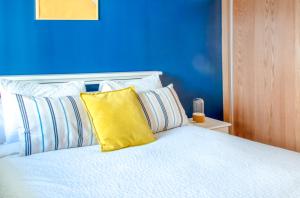 ラバトにあるLuxury Apartment 3 Bedroom in the Heart of Agdal near Arribat Centerの青い壁のベッドルーム1室、黄色い枕付きのベッド1台が備わります。
