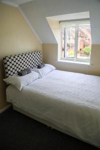 ChurchdownにあるLuxe Cosy&Spacious 2 Bed House - Super Fast Wi-Fi & Private Parking Near GLO Airport & Cheltenham Racecourseのベッドルーム(大きな白いベッド1台、窓付)