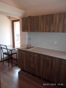 cocina con armarios de madera, fregadero y mesa en Phudze en Tʼelavi