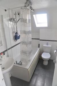 a bathroom with a tub and a toilet and a sink at Luxe Cosy&Spacious 2 Bed House - Super Fast Wi-Fi & Private Parking Near GLO Airport & Cheltenham Racecourse in Churchdown