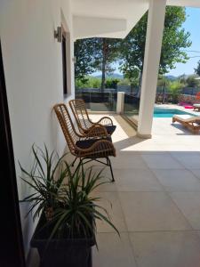 due sedie di vimini e una pianta in vaso su un portico di Luxury Villa Anemone with private pool a Pastida