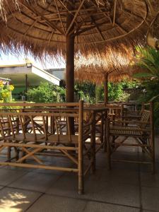 a wooden table and chairs under a straw umbrella at Anantra Pattaya Resort in Pattaya