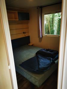 uma pequena cama num pequeno quarto com uma janela em Vacances en Provence em La Roque-dʼAnthéron