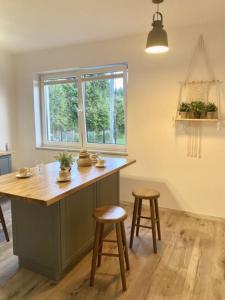 a kitchen with a island with two stools and a window at Apartamenty na Wzgórzu Boho 1 in Zagnańsk