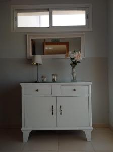 a white dresser with a vase of flowers and a mirror at APARTAMENTOS TURISTICOS LAS CINCO JOYAS in Linares +68 photos