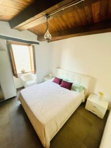 - une chambre avec un grand lit blanc et des oreillers rouges dans l'établissement San Nicolò Holiday Home, à Montalbano Elicona
