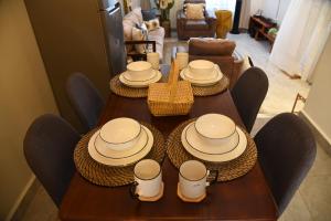 een houten tafel met stoelen, hoeden en borden erop bij Gamaleo Apartment Namulanda in Namulanda