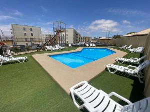 a swimming pool with lounge chairs and a slide at Cómodo departamento en Caldera, con piscina. in Caldera