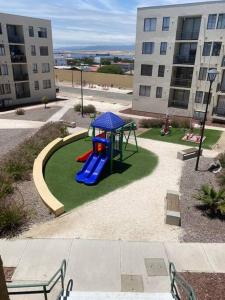 a playground with a slide in a courtyard in a building at Cómodo departamento en Caldera, con piscina. in Caldera