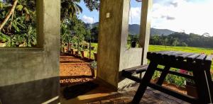 une véranda avec un banc et une vue sur un champ dans l'établissement Rain Forest Star, à Deniyaya