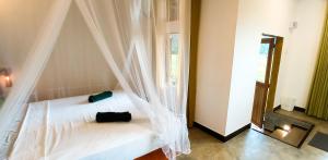 1 dormitorio con cama blanca y mosquitera en Rain Forest Star en Deniyaya