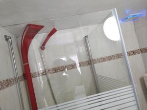 una puerta de ducha de cristal con mango rojo en el baño en Parve, en Bat Yam