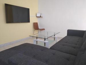 sala de estar con sofá, mesa y TV en Parve, en Bat Yam