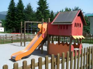 a playground with a slide in front of a fence at Studio 4 personnes au pied des piste plateau de Bonascre - Ax 3 domaines Eté Hiver in Ax-les-Thermes