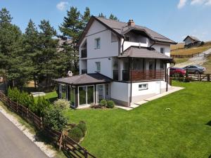 una gran casa blanca con un patio con césped verde en Vila Dzavric en Zlatibor