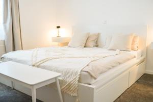 a white bedroom with a white bed and a table at Ferienwohnung Im alten Feld in Schmallenberg