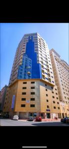 a large blue building with cars parked in front of it at Al Hayat Suites Apartment in Manama