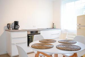 a white kitchen with a white table and chairs at Ferienwohnung Im alten Feld in Schmallenberg
