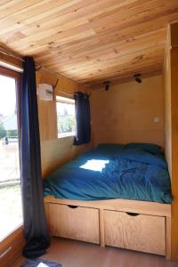 - un lit dans une petite maison dotée d'un plafond en bois dans l'établissement Roulotte dans les Ardennes, à Belval