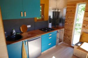 une cuisine avec des placards bleus et un comptoir dans l'établissement Roulotte dans les Ardennes, à Belval