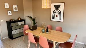 een eetkamer met een houten tafel en roze stoelen bij BeCosy Appartement 6 pers 2 chambres à Leuze in Leuze-en-Hainaut
