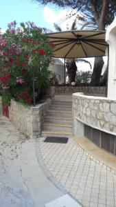une terrasse avec un parasol et des escaliers fleuris. dans l'établissement Venere Holidays, à Altavilla Milicia