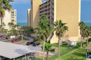 an apartment building with palm trees and a parking lot at Villa Del Sol Villa Views in Corpus Christi