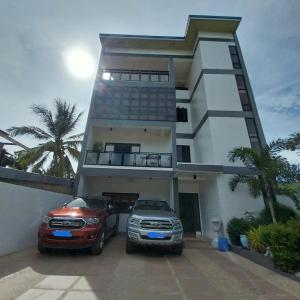 une voiture et une voiture garées devant une maison dans l'établissement Marinduque Bed and Breakfast, à Maniwaya