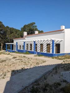 un edificio bianco con finiture blu accanto a una spiaggia di Ocean & Countryside Apartments a Encarnação