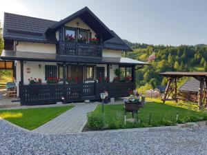 uma casa com uma varanda com flores em Casa Izvorul Rarăului em Câmpulung Moldovenesc