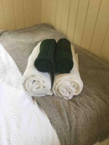 uma cama com toalhas brancas e verdes em Shepherd's Hut. Shower & WC. Deck. Amazing view em Longhope