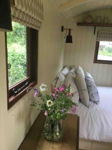 um quarto com um vaso de flores sobre uma mesa em Shepherd's Hut. Shower & WC. Deck. Amazing view em Longhope