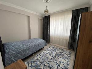a bedroom with a bed and a window and a rug at DALAMAN 2+1 GENİŞ KİRALIK DAİRE in Dalaman