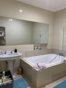 y baño con bañera y lavamanos. en Relaxinhaatso - 4 Bedroom luxury house with pool, en Haatso