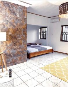 a bedroom with a bed and a stone wall at Relaxinhaatso - 4 Bedroom luxury house with pool in Haatso