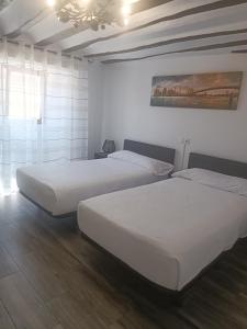 Habitación con 2 camas, paredes blancas y suelo de madera. en Hotel Rural Quintanapalla, en Quintanapalla