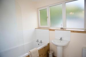 a white bathroom with a sink and a window at Lochleven Seafood Cottage in Onich +11 photos