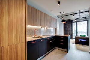 a kitchen with black cabinets and a sink at Wembley Park Modern Flat in London