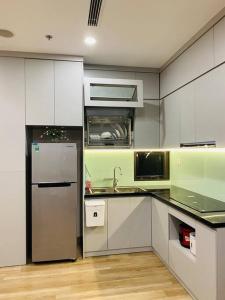 La cuisine est équipée de placards blancs et d'un réfrigérateur en acier inoxydable. dans l'établissement 2PN sân vườn Solforest, Ecopark, à HÆ°ng YÃªn